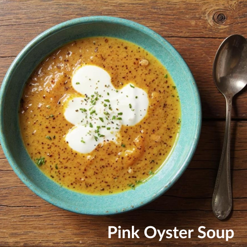 Bowl of pink oyster soup with a spoon on a wooden table